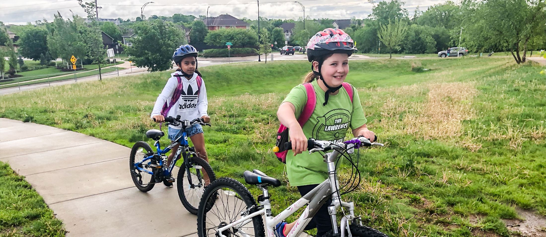 Two girls riding their bikes with helmets on